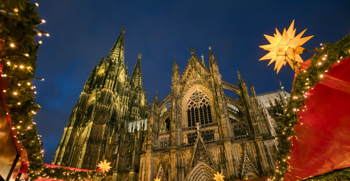 The Cologne Christmas Market in Germany, featuring festive stalls, a grand Christmas tree, and the iconic Cologne Cathedral in the background.