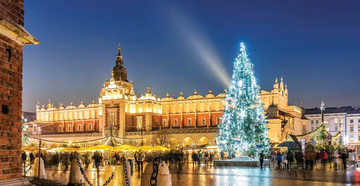 The Krakow Christmas Market in Poland, featuring festive stalls, a brightly lit Christmas tree, and the historic Cloth Hall in the background.