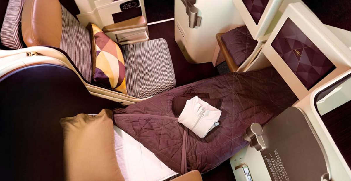 A luxurious business class lie-flat seat on an airplane, featuring plush bedding, ample legroom, and a personal entertainment screen.