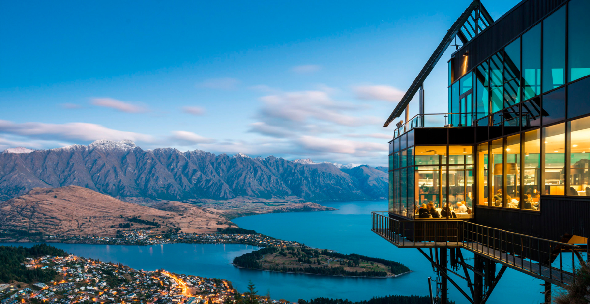 Queenstown skyline view with mountains, lake, and a glass-walled restaurant.